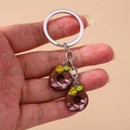 Close-up of a keychain featuring two chocolate donuts with yellow roses and pink vines - Brown Flower