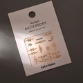 Close-up of gold nail charms and rhinestones on MJ-011 display card on grey background - MJ-011 Gold Foil Style