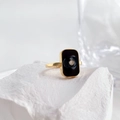 Detailweergave van een gouden vierkante ring met zwart emaille en een centrale diamant - US 6 / Vierkante Stijl