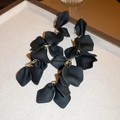 Primer plano de pétalos negros mates y pendientes de borla de metal dorado de moda - Borla de Pétalos de Rosa / Negro