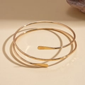 Close-up of golden spiral upper arm cuff with hammered texture finish on the ends - Gold