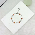 Detail view of 18k gold daisy and star charms on a stainless steel link bracelet - Red Silver