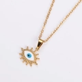 Close-up of golden oval evil eye pendant necklace with blue eye detail and starburst edges - Gold Color White Eye