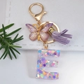 Letter E keychain with purple sequins, gold butterfly charm and tassel on a white card - Letter E