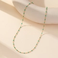 Detailed shot of gold collar chain with small bright green enamel beads on white prop - Gold Chain Green Enamel Beads