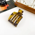 Detail of tortoise shell claw clip with cutout design on white marble background - Matte Yellow Coffee