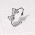 Minimalist silver bow open ring with textured rope band on white stone background - Steel