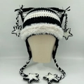 Striped knit cat ear hat with white plush trim and star pendants on beige model head - Black & White Stripes