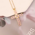 Macro detail of gold cross pendant with pink square gemstones and zircon inlays - Pink