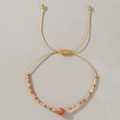Primer plano de la pulsera tejida con cuentas de tonos cálidos y nudo corredizo ajustable - Piedra Texturizada Naranja Trenzada