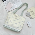 Borsa in tela con fiocchi blu, pizzo e motivi a quadri tra vari oggetti quotidiani - Spalla Beige