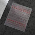 Détail macro de stickers d'ongles 3D avec nœuds rouges et cœurs aux accents dorés - CO-546 / Or Rouge Métallique