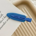 Detailed close-up of a matte dark blue seamless hair clip on a minimalist tray - Fluorescent Blue