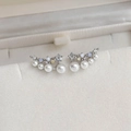 Macro detail of silver curved earrings with white pearls and blue zircon accents - 14# 25070B Silver Curved Pearl