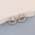 Detail of silver oval hoop earrings with hammered texture on a marble surface - Silver Hammered Texture Hoop