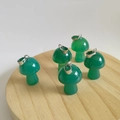 Five mini mushroom-shaped green agate stone pendants with silver metal clasps on a tray - Synthetic Green Stone