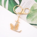 Detail view of golden metal letter L keychain with butterfly and sparkling crystals - Letter L