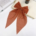Macro detail of caramel polka dot sheer chiffon fabric and double-layered bow hair clip - Brick Red