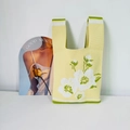 Détail de la texture tricotée et des motifs floraux blancs sur un sac jaune - Fleur de Cerisier Beige