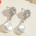 Détail de boucles d'oreilles perles baroques et fleurs en cristal sur fond beige - Boucles d'oreilles clous en perles irrégulières et pavé de zirconiums argentés