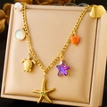 Gouden rvs oceaan armband met zeester, schildpad en schelp hangers op een beige doosje - Goud - Zeedier Multi-Hanger (N2895)