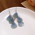 Detailed close-up of blue resin flower petal earrings with silver sequin accents on ceramic - Silver-Blue Gradient Petal