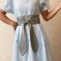 Détail de la ceinture corset grise en similicuir avec un nœud sur une robe bleue - Gris