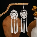 Detail of silver bohemian earrings with leaf tassels hanging on a natural wooden branch - Disc Hollow Tapered Tassel