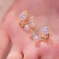 Macro-opname van gouden visstaart oorbellen met iriserende parels en zirkonia - Gouden Vissenstaart Parel Oorknopjes