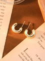 Detail view of chunky golden C-shaped hoop earrings on vintage printed paper - Gold Small C-Shape
