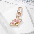 Detailed macro view of a golden fan-shaped resin keychain with real pink dried flowers - Pink Flower Fan