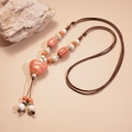 Detail van roze keramische harthanger ketting met bruin gevlochten koord en kralen - Roze