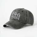 Detailed close-up of DOG MOM embroidery and washed denim texture on a dark grey baseball cap - Black