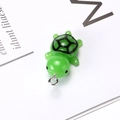 Detailed close-up of a green resin turtle pendant with realistic shell patterns and metal ring - Turtle