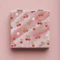 Close-up of portable makeup mirror featuring red cherry patterns and metal hinges - Cherry / Pink