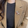 Detail van een fonkelende rendierbroche met strasstenen op de revers van een beige blazer - Zilver-Roodneusrendier (Broche)