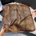 Fashionable leopard print square silk scarf with glossy satin finish on plush background - Brown Leopard