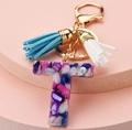Detail shot of resin letter T keychain with colorful stones, golden hook and blue tassel - Letter T