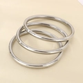 Detailed view of three polished silver hollow stainless steel bangles set on white background - Steel Color 3-Piece Set