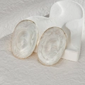 Macro detail of oval stud earrings featuring white marble oil drip effect and gold plating - Marbled White / White