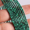 Strands of 2mm green malachite round gemstone beads held in hand for DIY jewelry making - Malachite