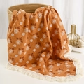 Detailed texture of burnt orange muslin baby blanket with white daisy prints and tassel fringe - Orange Flower