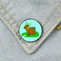 Macro detail of a cute capybara in frog hat badge pinned on blue denim fabric - Frog Hat Capybara