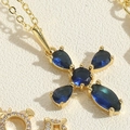 Macro view of gold plated cross necklace featuring a deep blue zircon gemstone inlay - Royal Blue Zirconia Cross (XL2658)