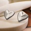 Detailed close-up of 3D silver heart-shaped stud earrings on a textured pedestal - Heart / Silver Heart