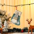 Close-up of green burlap Christmas stocking with gnome doll and HO HO text hanging on a branch - Sky Blue