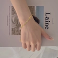 Detail of 18K gold plated flat cross chain necklace worn against a magazine background - Gold Bracelet