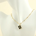 Detailansicht einer schwarzen Emaille-Briefumschlag-Halskette mit Goldherz am Modell - Schwarzer Umschlag