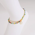 Colorful beaded layered anklet with gold flower pendant on white foot model - Anklet