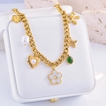 Detalle de collar bohemio dorado con corazón de perla y dijes de flores en un joyero - Flor de Cinco Pétalos